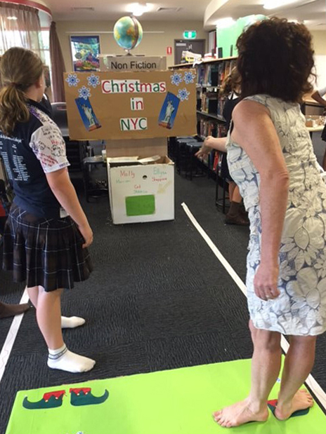 A teacher and a student playing a homemade arcade game in a library