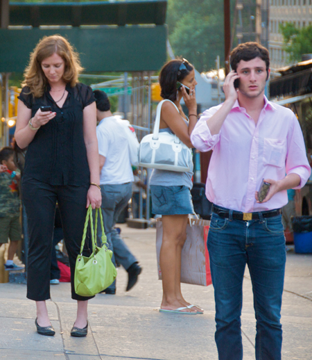 People standing close together in public but all using their phones.