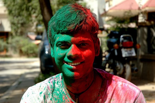 A man celebrating Holi Hai!, covered with green and red powder.