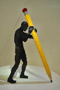 Lego sculpture of a man holding a giant pencil