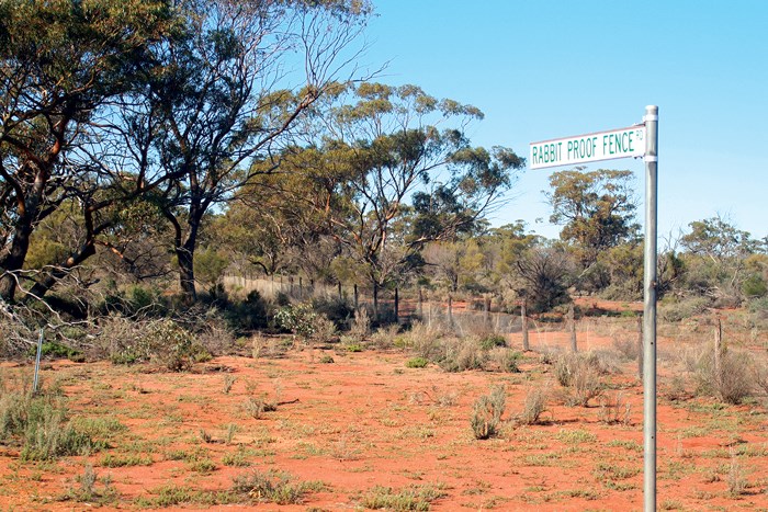 Photograph of the outback with a street sign that says Rabbit Proof Fence St
