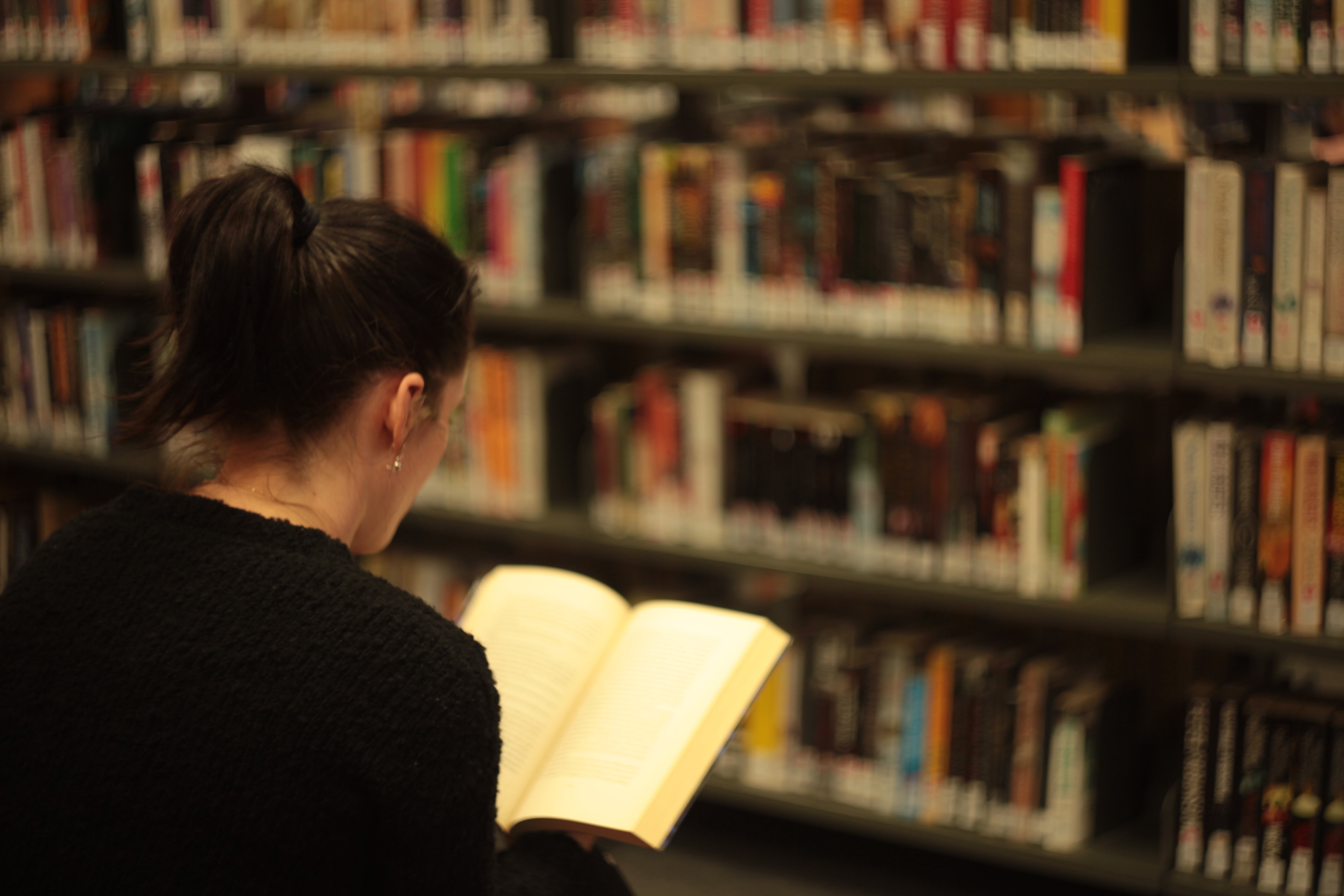 Woman sitting in a library reading a book