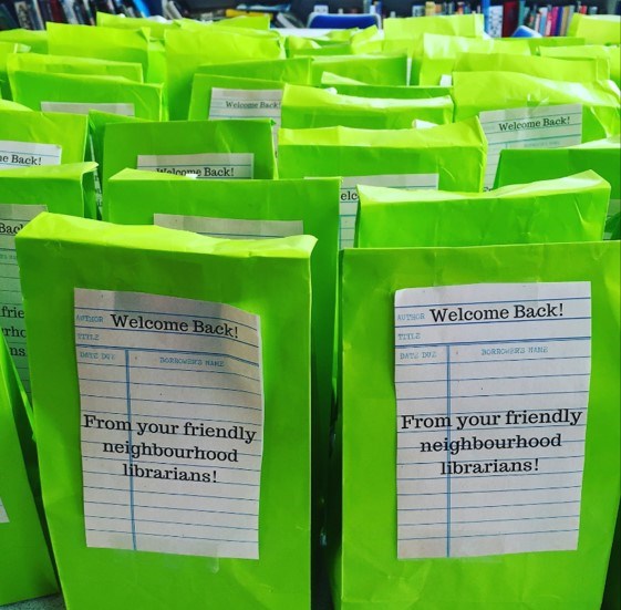 Green welcome back bags filled with goodies to encourage people to visit their local library