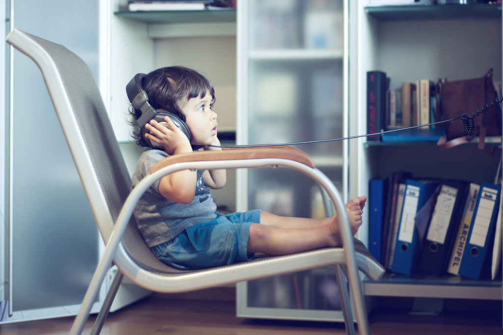 Small child sitting on a chair wearing headphones