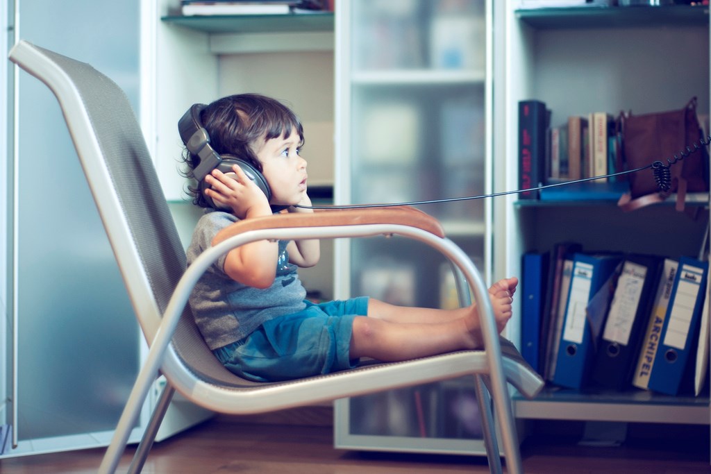 Small child sitting on a chair wearing headphones