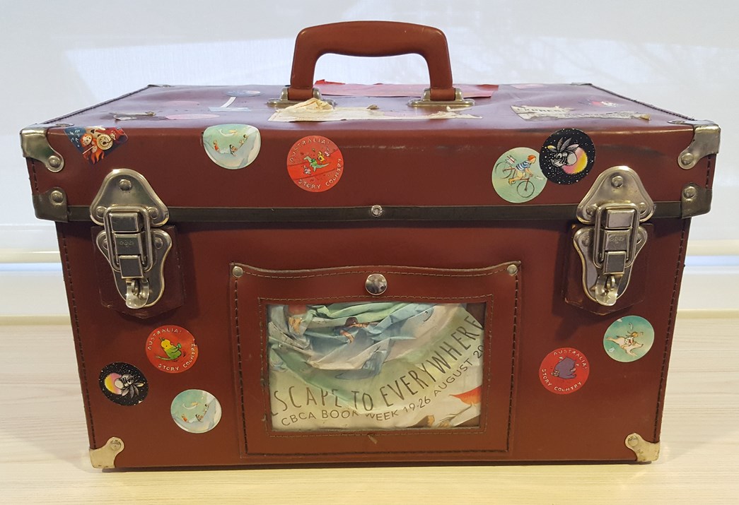 A vintage suitcase covered in Book Week stickers used as a prop