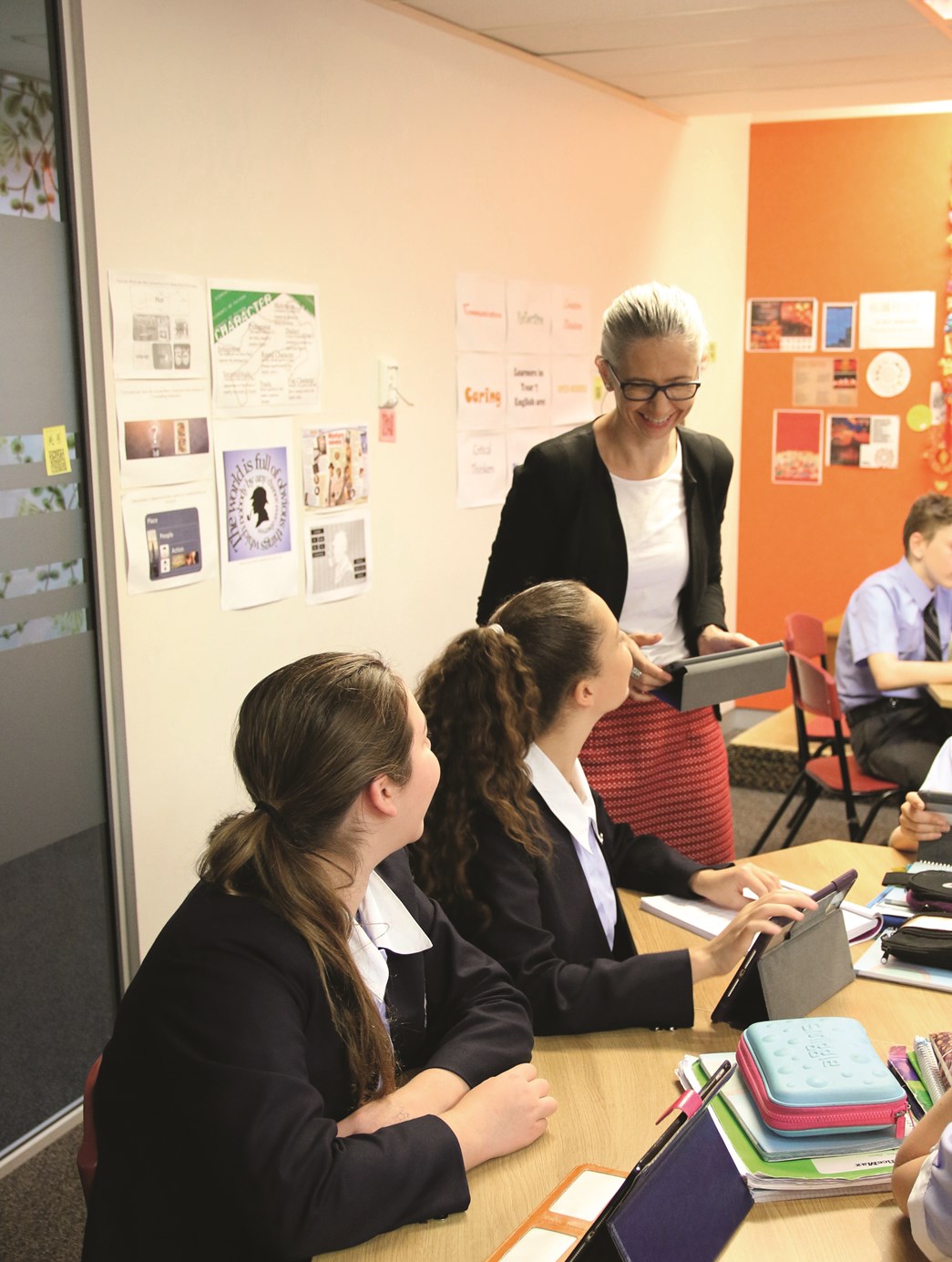 Teacher standing next to two students working on tablets