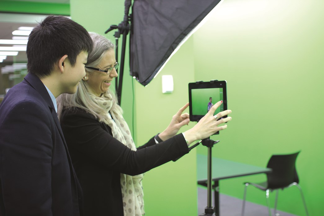 Teacher showing student how to use a greenscreen with a tablet