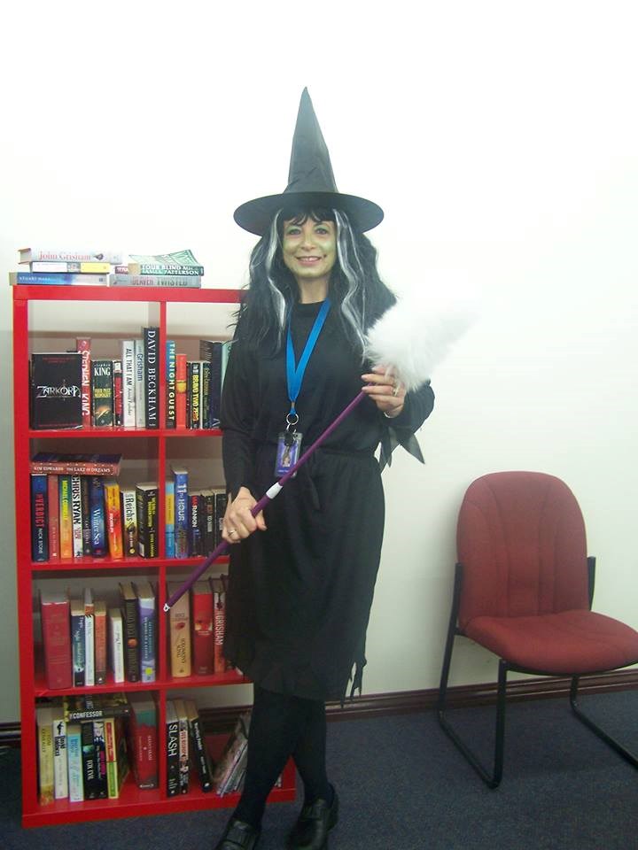 Helen Tomazin, dressed up as a witch for Book Week, stands in her staff room surrounded by hand-picked books.