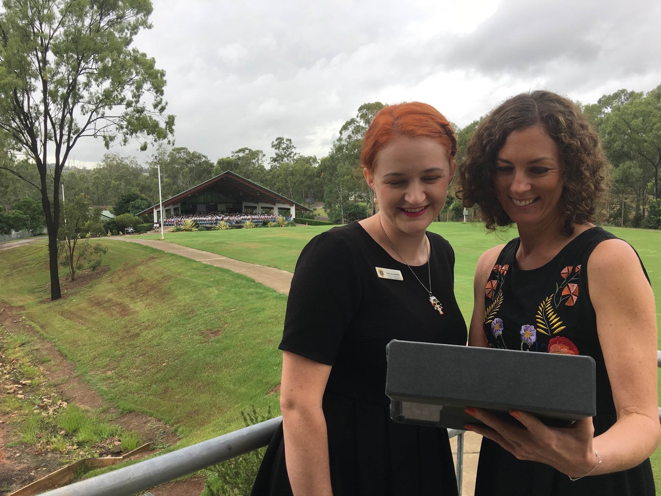 Two librarians standing outside using a tablet