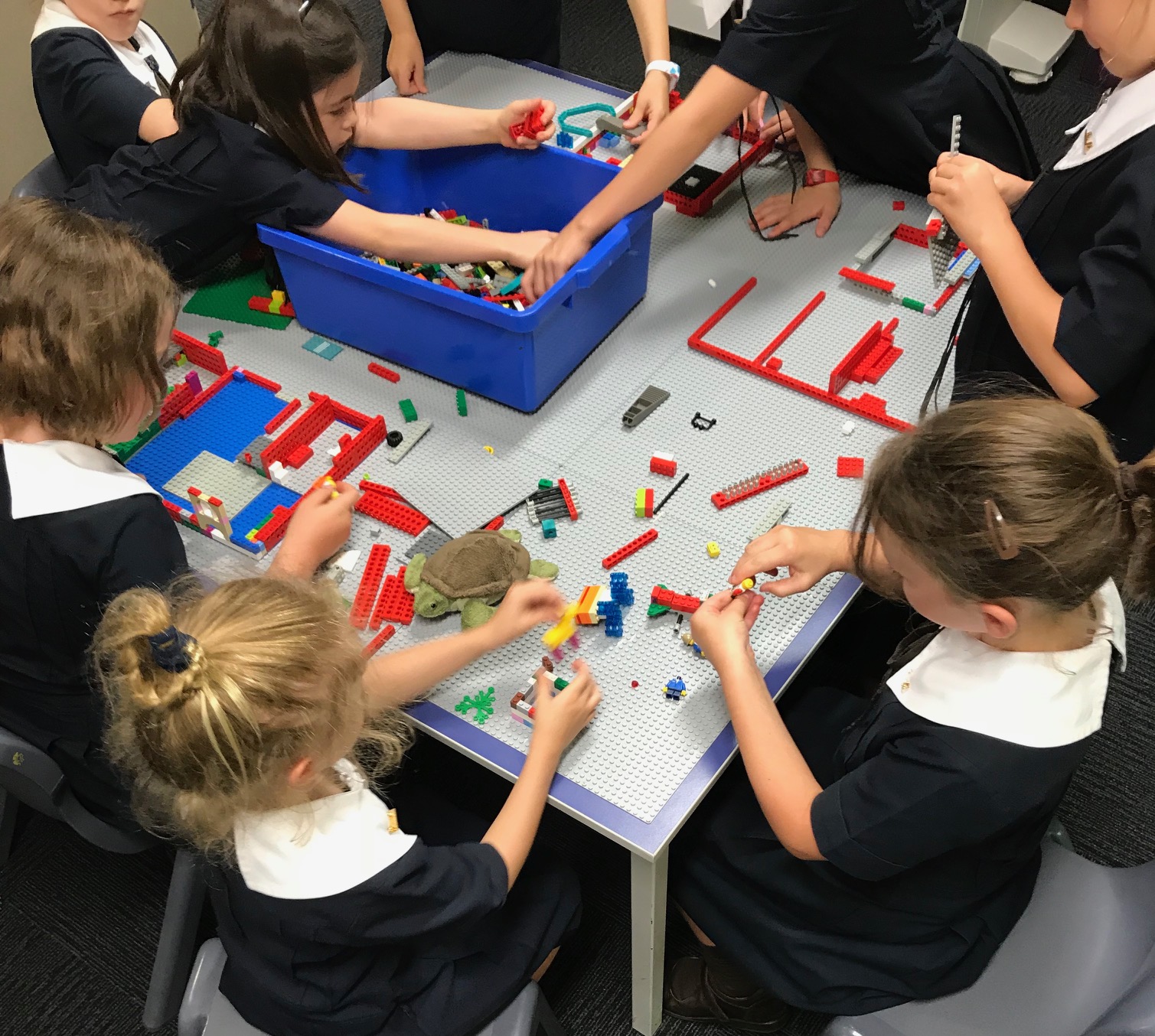 Children building together with connecting blocks around a table