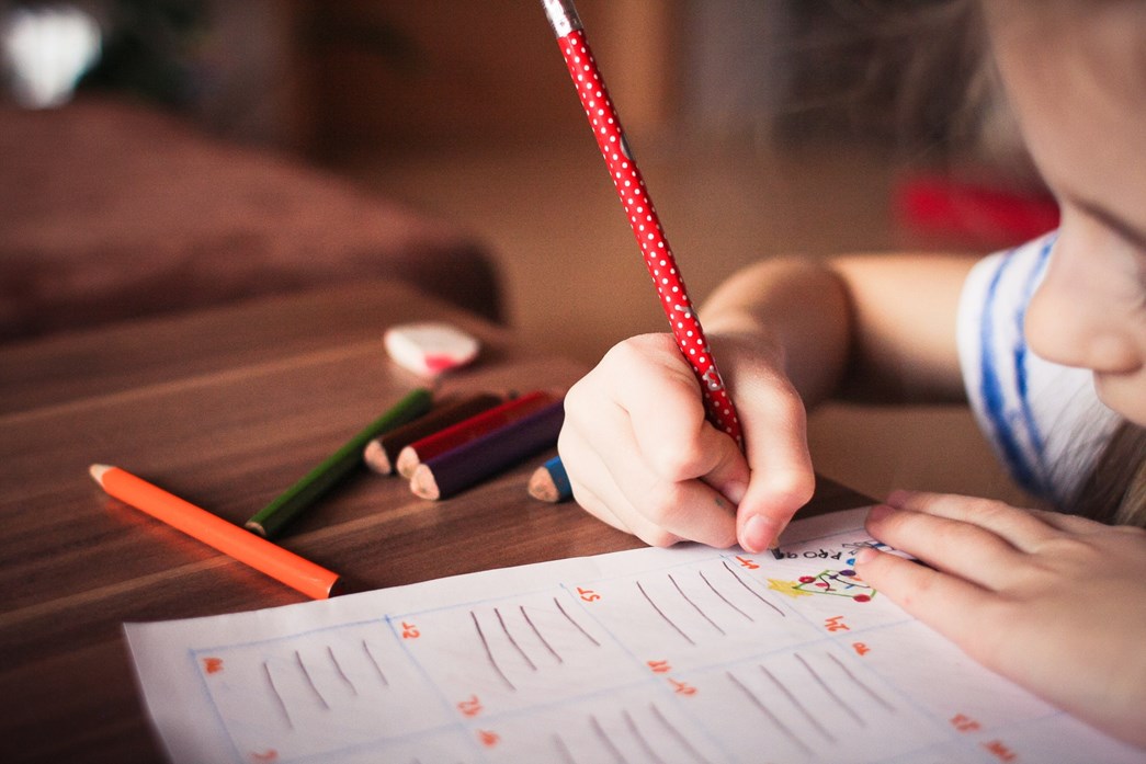 Child drawing on a piece of paper with colouring in pencils