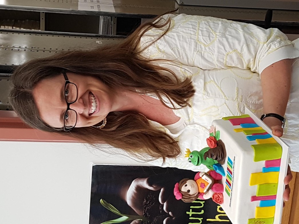 Holly Godfree holding a cake to celebrate the launch of the Students Need School Libraries campaign in late 2018.