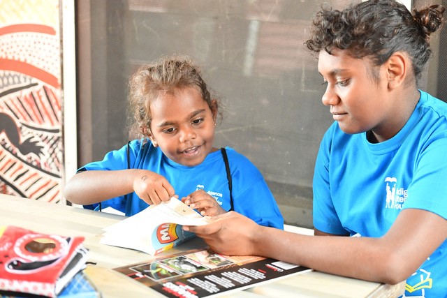 Two girls in blue shirts reading together