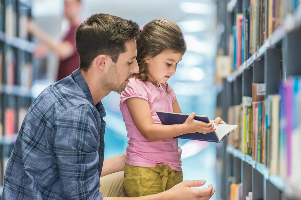 Parent and child reading a book in library