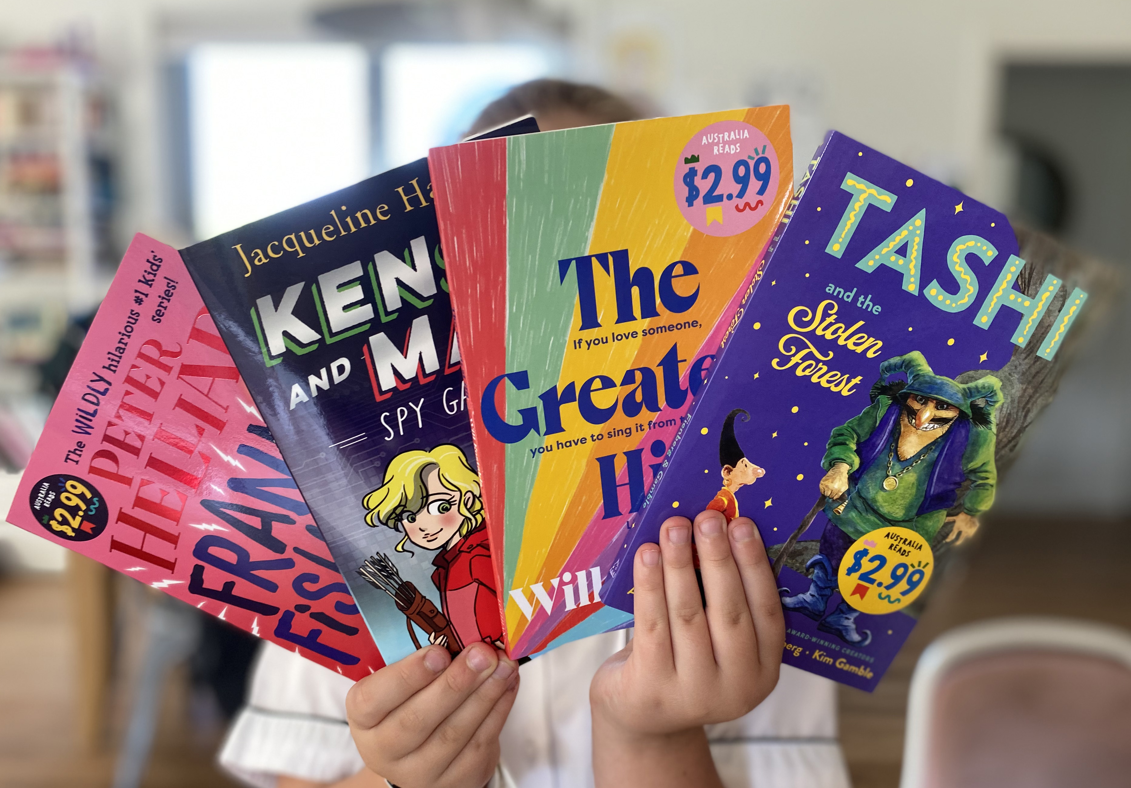 Person holding four Australian books.