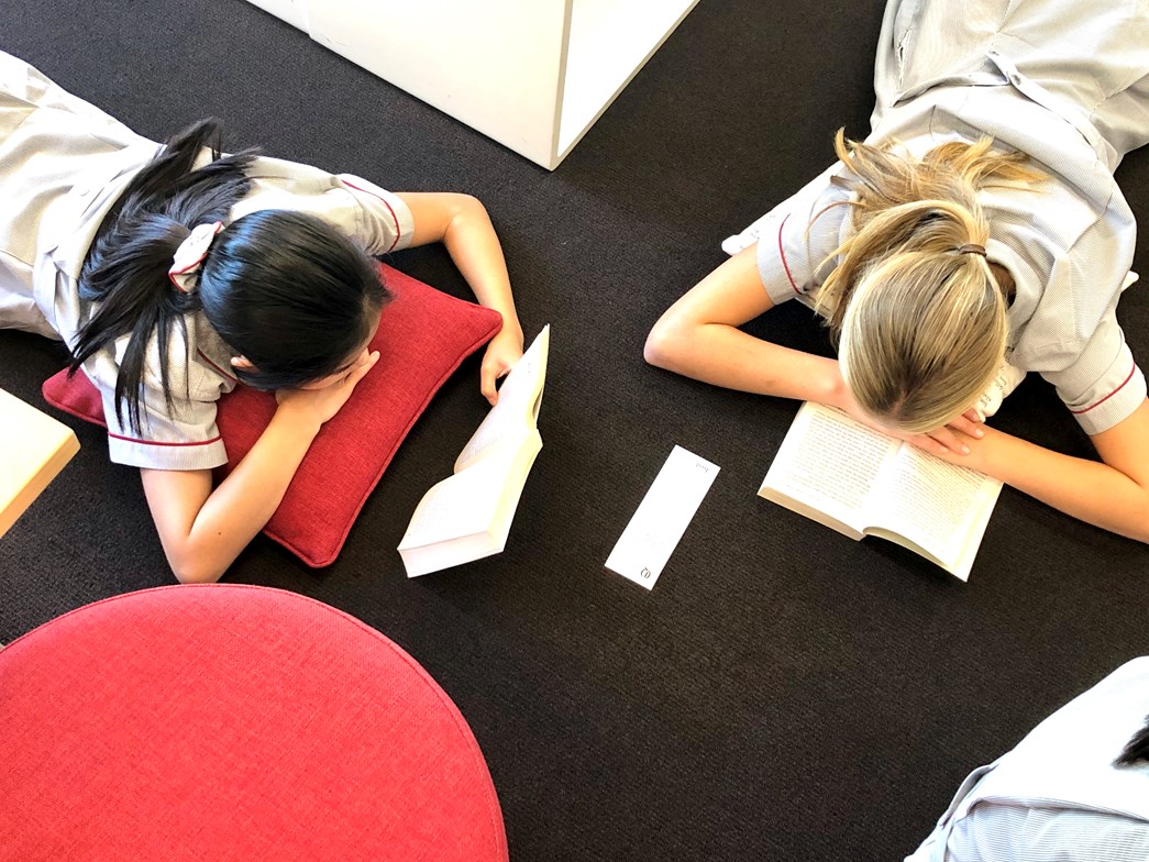 Students laying on the floor reading