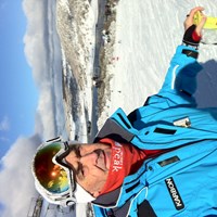 A headshot of Lance Deveson. He is pictured in a ski suit, standing at the top of a snow covered slope