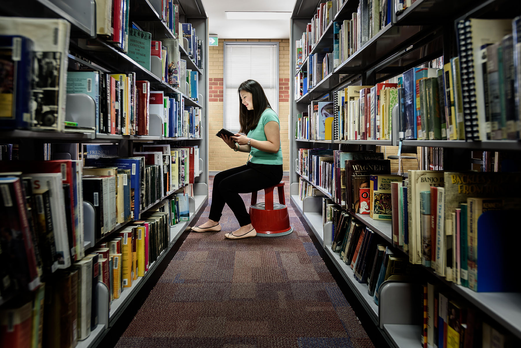 Librarian reading a book in the aisle of a library