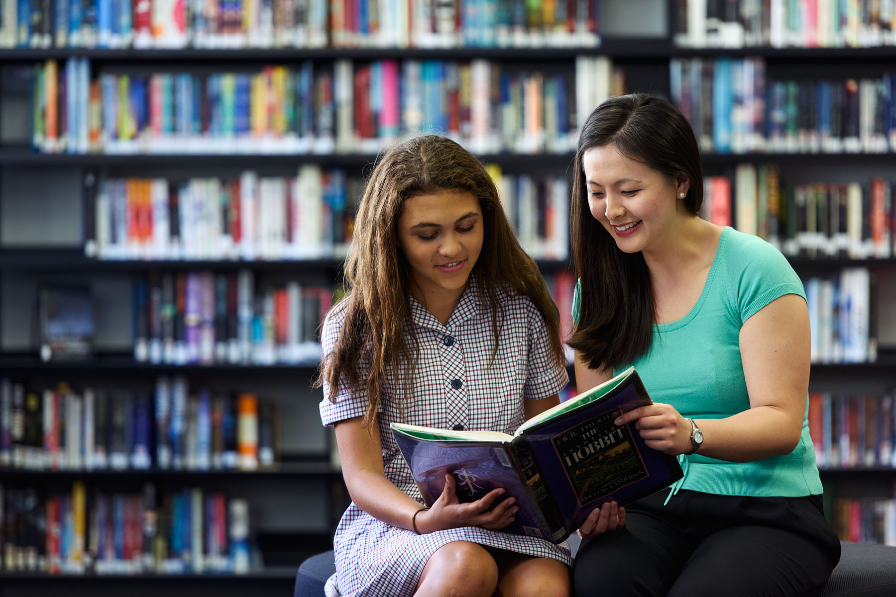 Teacher and Student reading together in a library
